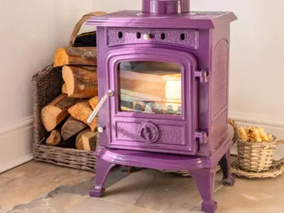 a purple stove sitting next to a pile of logs at The Bothy - your unique luxury refuge in Saint Fillans