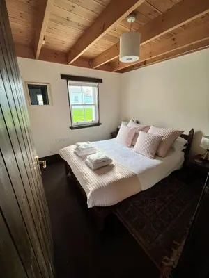 a bedroom with a large bed with white sheets and pillows at Easdale Cottage in Ellanbeich