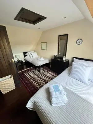 a bedroom with two beds and a mirror at Easdale Cottage in Ellanbeich