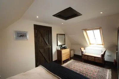 a bedroom with a bed and a window and a wooden door at Easdale Cottage in Ellanbeich