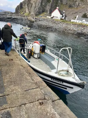two people getting on a small boat at a dock at Easdale Cottage in Ellanbeich