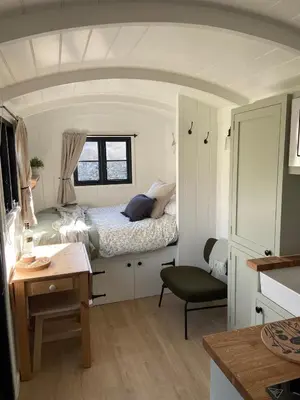 a small bedroom with a bed and a desk at Peaceful Shepherd’s Hut in beautiful countryside. in Linlithgow