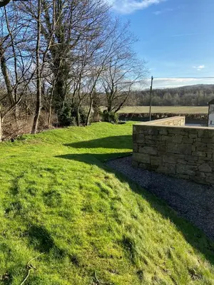 a grassy field with a stone wall and trees at Peaceful Shepherd’s Hut in beautiful countryside. in Linlithgow