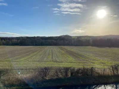 a large open field with the sun in the sky at Peaceful Shepherd’s Hut in beautiful countryside. in Linlithgow