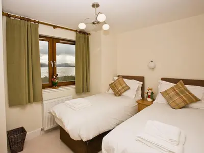 two beds in a room with a window at The Quaich in Stron-fearnan