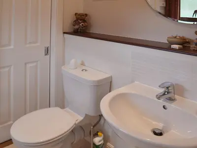 a bathroom with a toilet and a sink and a teddy bear at The Quaich in Stron-fearnan