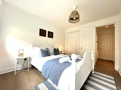 a bedroom with a white bed with a blue blanket at Bellevue Apartment in Largs