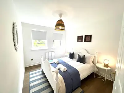 a bedroom with a white bed with a blue blanket at Bellevue Apartment in Largs