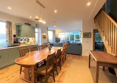 a kitchen and dining room with a wooden table and chairs at The Neuk in Tighnabruaich