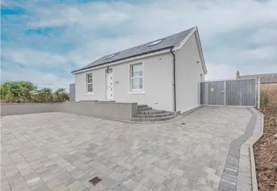 a white house with a fence and a patio at 5 Bed cottage with Hot tub in Bannockburn