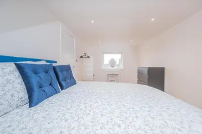 a white bedroom with a large bed with blue pillows at 5 Bed cottage with Hot tub in Bannockburn