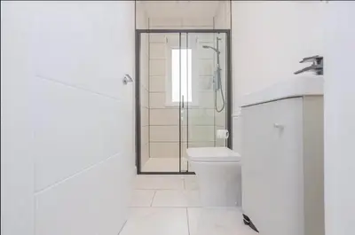 a white bathroom with a shower and a toilet at 5 Bed cottage with Hot tub in Bannockburn