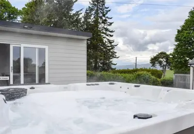 a jacuzzi tub in front of a house at 5 Bed cottage with Hot tub in Bannockburn