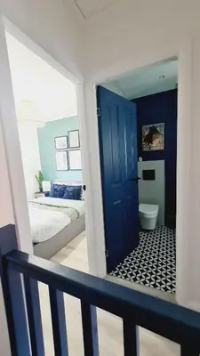 a bathroom with a blue door and a bedroom with a bed at Beautiful 2bed house with garden, walking distance to town - FREE parking in Glasgow