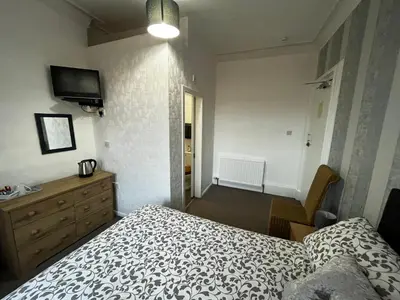 a bedroom with a bed and a dresser and a television at Dunarle Guesthouse in Oban