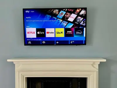 a flat screen tv above a fireplace at Ballachulish House Apartment in Ballachulish