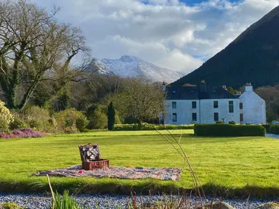 a bench in a field with a house in the background at Ballachulish House Apartment in Ballachulish