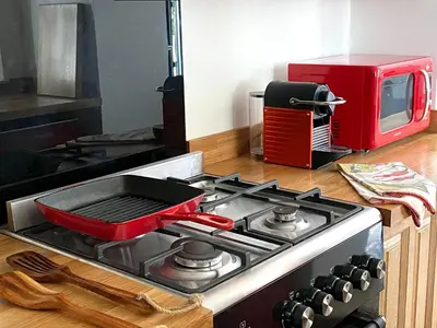 a stove top with a red pan on top of it at The Bothy of Ballachulish House in Ballachulish