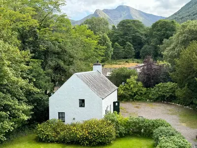 a white house in the middle of a field at The Bothy of Ballachulish House in Ballachulish
