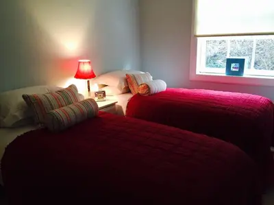 a bedroom with two beds with red blankets and a lamp at Viking Cottage in Arrochar