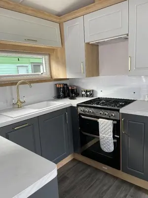 a kitchen with a black stove and white cabinets at Swift Bordeaux 67 in Dunoon