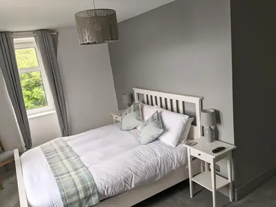 a bedroom with a white bed with pillows and a window at Lochaline Hotel in Lochaline