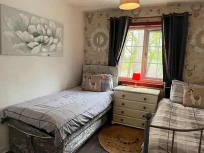 a bedroom with two twin beds and a window at Doocot At Bonnyside House - New Hot Tub Aug 2025 in Bonnybridge