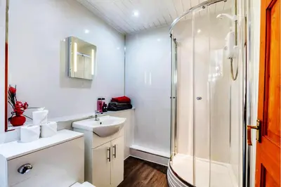 a white bathroom with a shower and a sink at Doocot At Bonnyside House - New Hot Tub Aug 2025 in Bonnybridge