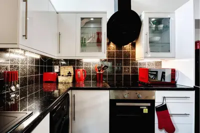 a kitchen with white cabinets and a black counter top at Doocot At Bonnyside House - New Hot Tub Aug 2025 in Bonnybridge