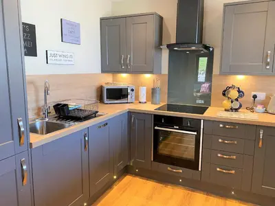 a kitchen with gray cabinets and a sink at Partridge Lodge with Hot Tub in Forgandenny