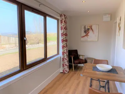 a dining room with a table and a window at Pheasant Lodge with Hot Tub in Forgandenny