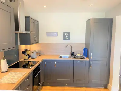 a kitchen with gray cabinets and a sink at Pheasant Lodge with Hot Tub in Forgandenny
