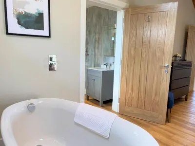 a white bath tub in a bathroom with a wooden door at Pheasant Lodge with Hot Tub in Forgandenny