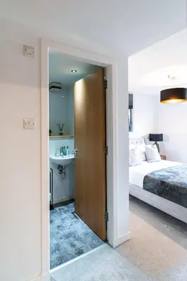 a bedroom with a bed and a bathroom with a sink at The Lusso Suite - 2BR - A 5* Escape Like No Other in Glasgow