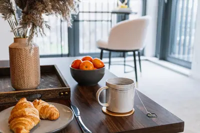 a table with a plate of croissants and a coffee mug at The Lusso Suite - 2BR - A 5* Escape Like No Other in Glasgow
