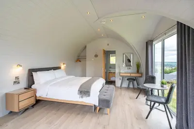 a bedroom with a bed and a desk and a table at The Vu Snugs in Bathgate