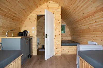 a small kitchen with an open door in a wooden cabin at Luxury Rural Ayrshire Glamping Pod in Dalmellington