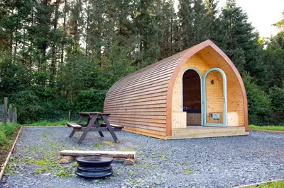 a small wooden tent with a grill and a picnic table at Luxury Rural Ayrshire Glamping Pod in Dalmellington