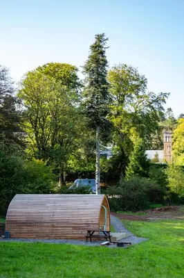 a large wooden structure in a park with a bench at Luxury Rural Ayrshire Glamping Pod in Dalmellington