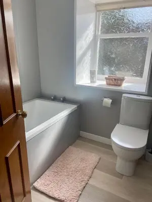 a bathroom with a toilet and a tub and a window at East Kelt Farm Cottage in Denny