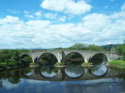 a bridge over a river with four arches at East Kelt Farm Cottage in Denny