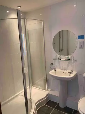a white bathroom with a shower and a sink at The Apartment - Chandlers in Ascog
