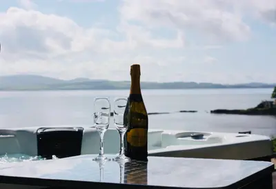 a bottle of wine sitting on a table with two glasses at Seaview Cottage Bute in Ascog