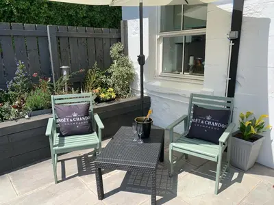 two chairs and a table with an umbrella on a patio at Seaview Cottage Bute in Ascog