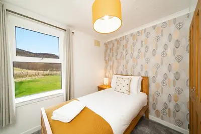 a small bedroom with a bed and a window at Lagnaha Cottage in Kentallen