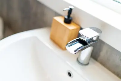 a bathroom sink with a wooden soap dispenser on it at Lagnaha Cottage in Kentallen