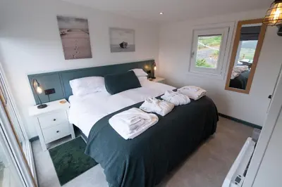 a bedroom with a large bed with towels on it at The Paddock- Loch Lomond and Trossachs in Gartmore