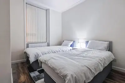two beds in a white room with a window at Glasgow Southside: Cosy 2 Bedroom Apartment in Glasgow