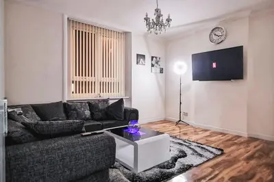 a living room with a couch and a tv at Glasgow Southside: Cosy 2 Bedroom Apartment in Glasgow
