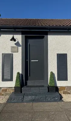 a black door on a house with two plants at Holly Lodge - 2 x Kingsize bedrooms with private entrance and free parking-new shower room in Oban